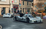 Porsche 963 RSP with 917 driving through town front quarter tracking