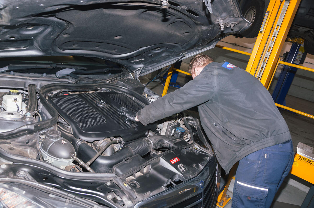 Mechanic inspecting engine at garage