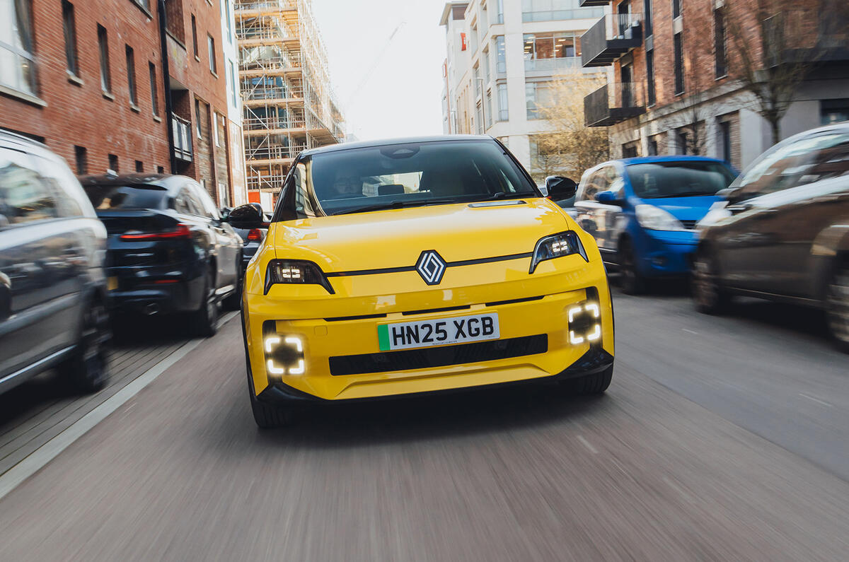 A Pop Yellow Renault 5 E-Tech electric driving through the city viewed from the front